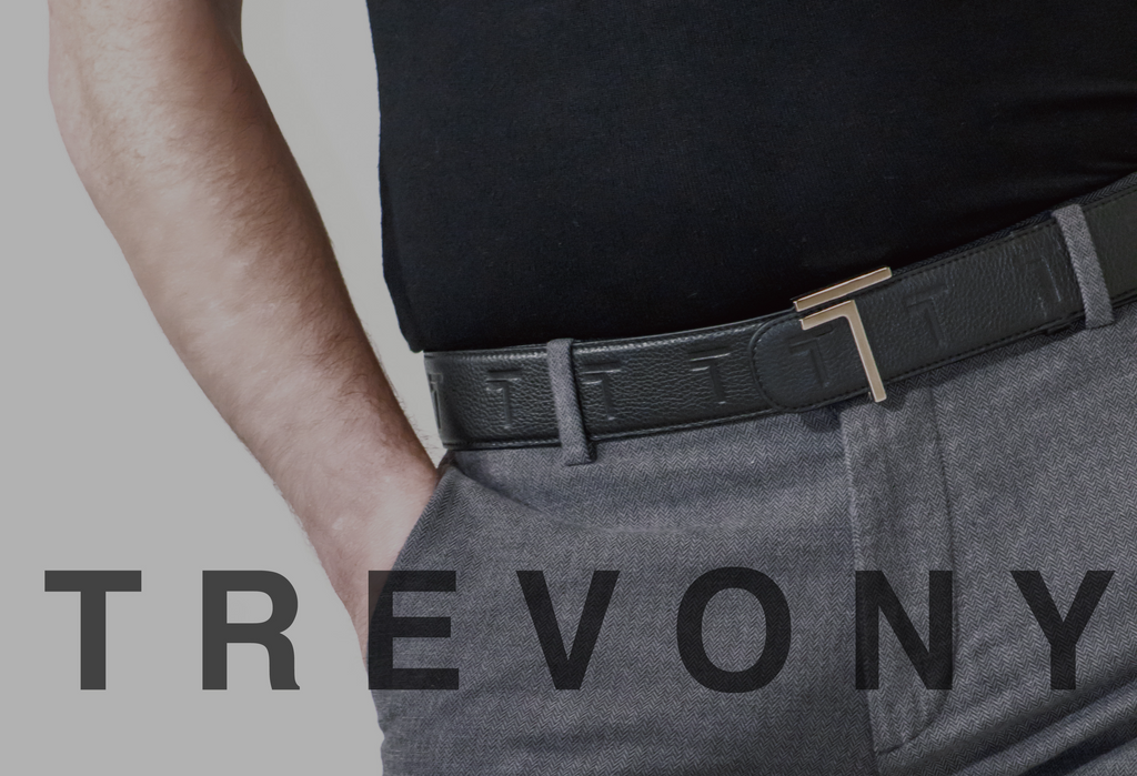 A close-up of a person wearing the Trevony Truth belt, showcasing the textured black leather and the belt’s sleek gold 'T' buckle.
